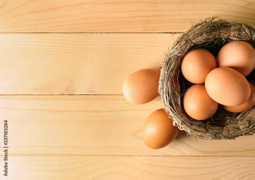 Nest with raw brown chicken eggs on wooden table