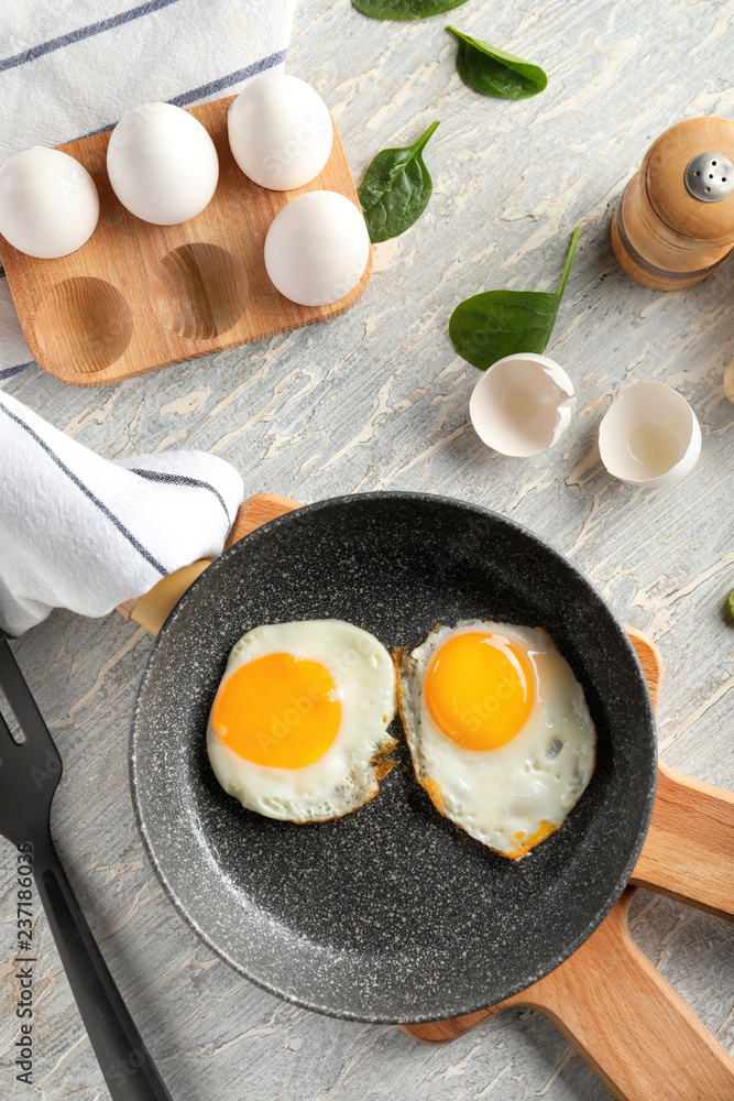 Pan with tasty fried eggs on wooden boards