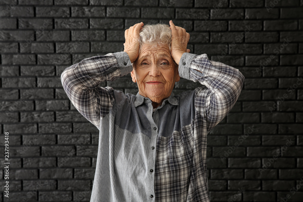 Portrait of elderly woman after making mistake on dark background