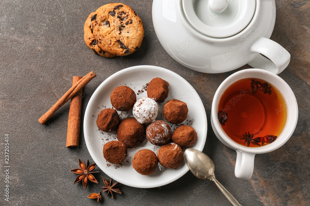 灰色桌子上摆着美味的巧克力松露和一杯茶