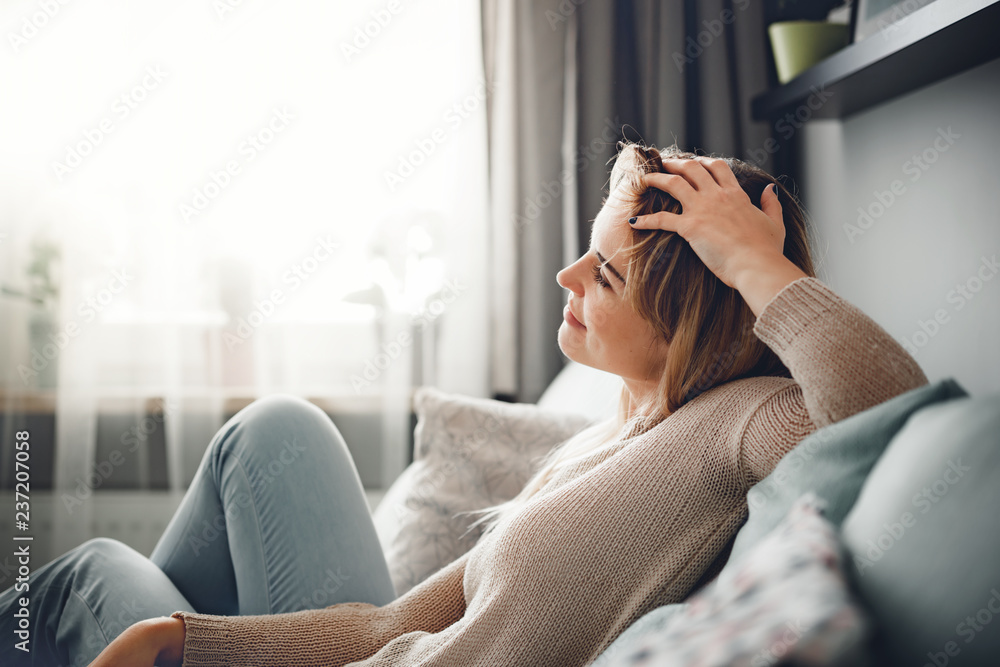 Cheerful smiling woman full of positive emotions sitting on sofa at home