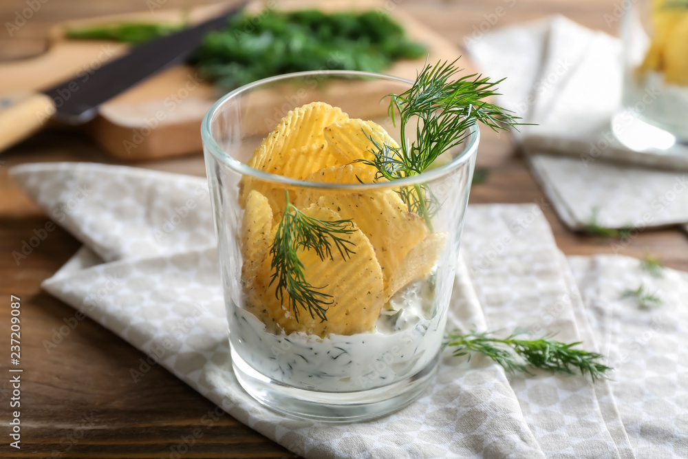 Tasty crispy potato chips with sour cream and dill in glass