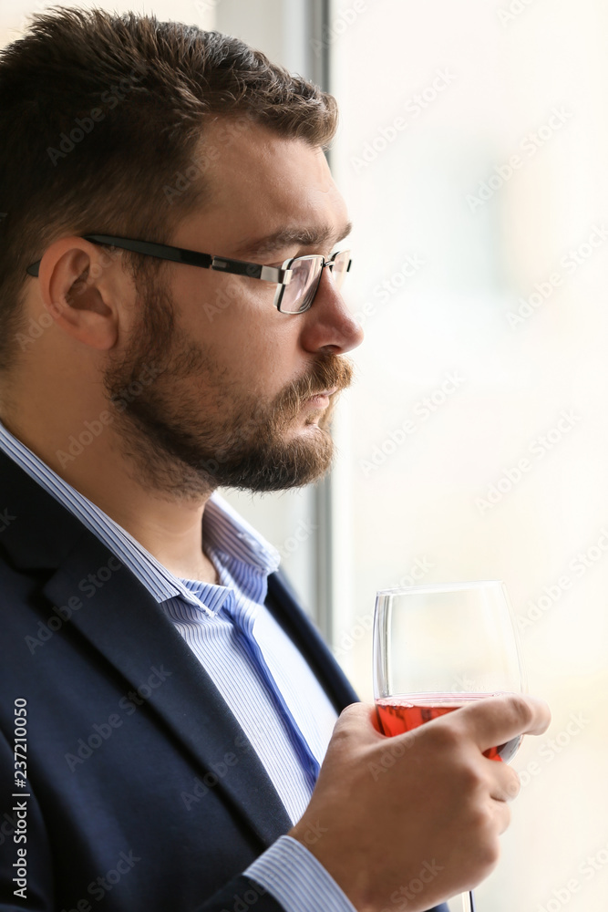 Businessman drinking wine near window