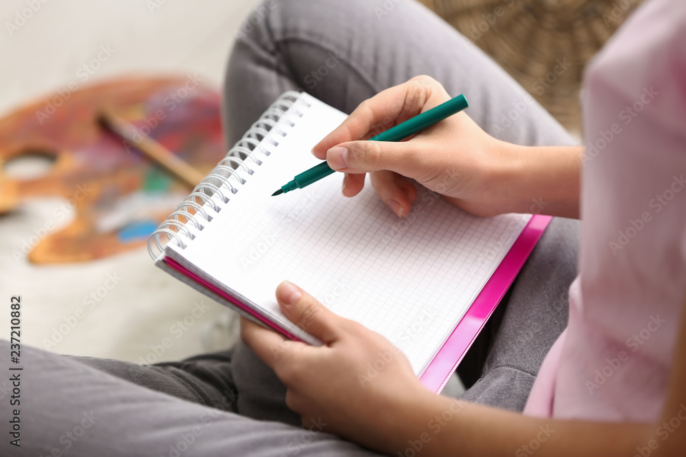 Young woman writing in notebook at home