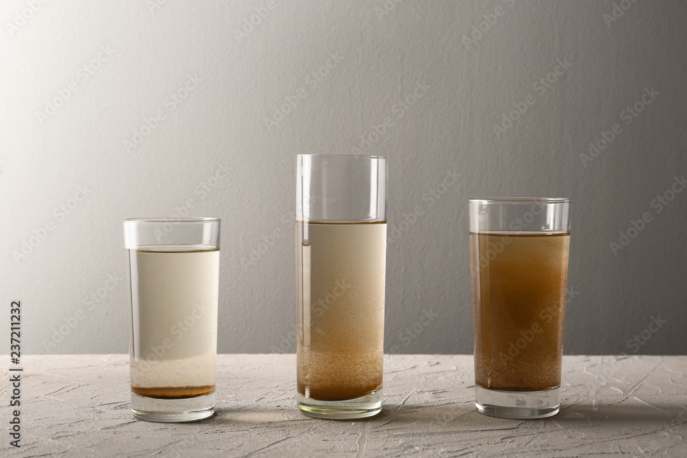 Glasses of dirty water on grey table