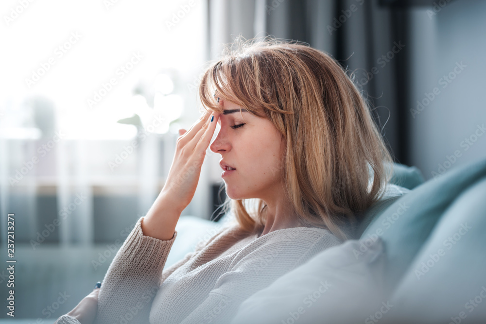 悲伤的女人坐在家里的沙发上，想着重要的事情