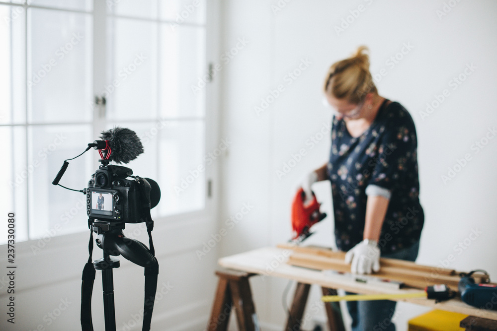 Female blogger ​​​​​​​​​​​​​​cutting a plank with a jigsaw machine