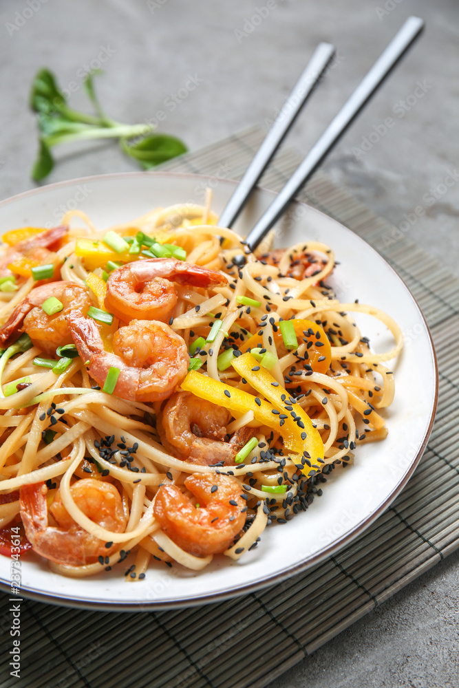 Plate with tasty chinese noodles and shrimps on table, closeup