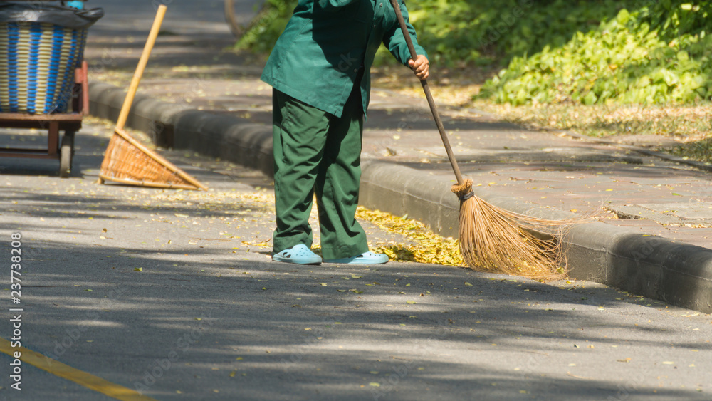 The cleaner is sweeping the garbage on the road.