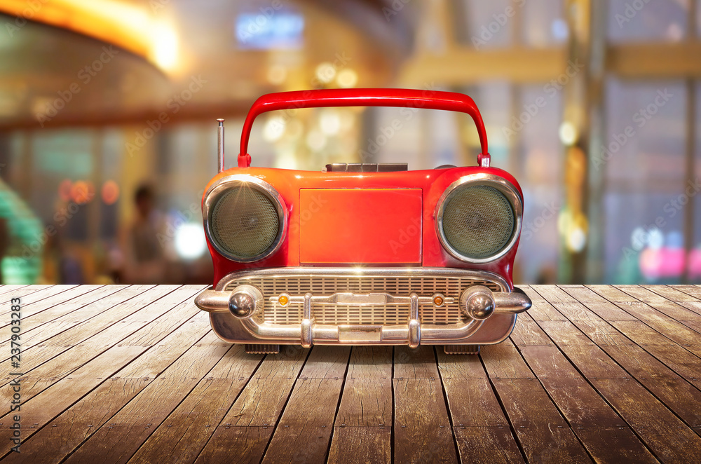 Old antique car shape AM FM stereo cassette player on wood table top with blur background