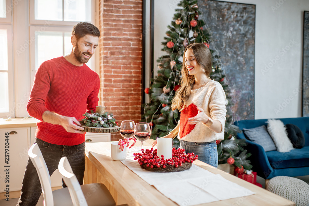 Young couple preparing for a New Year decorating their beautiful apartment standing in the dining ro