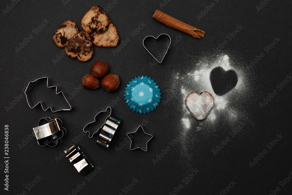 Cookies and baking equipment on black background