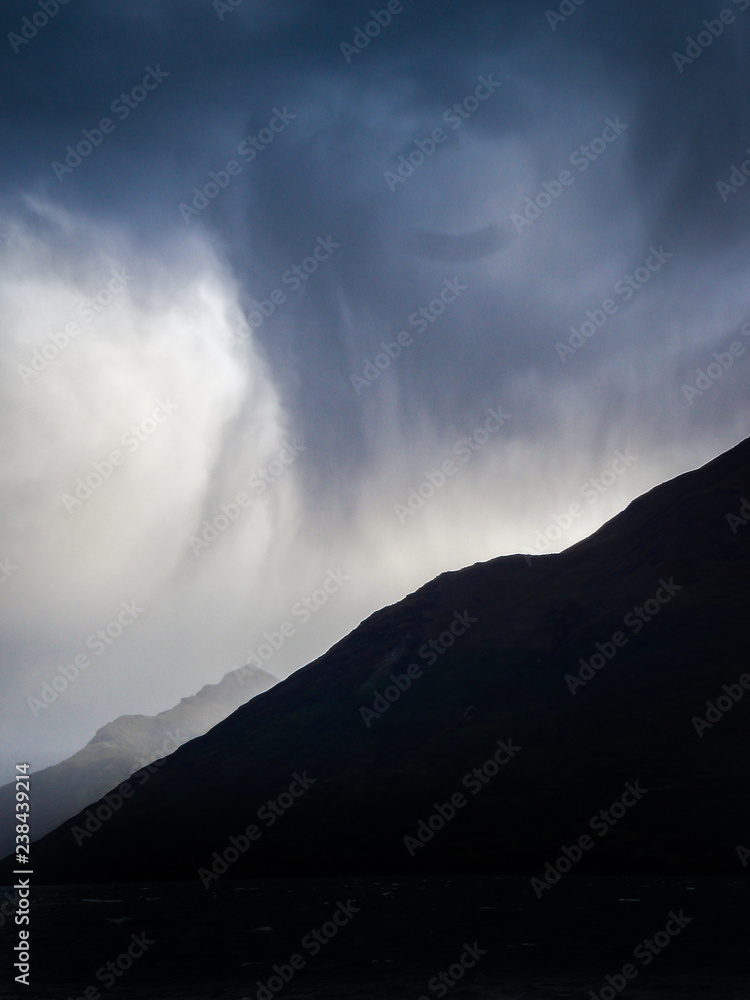 A silhouette of a mountain with rain cloudy hanging over it