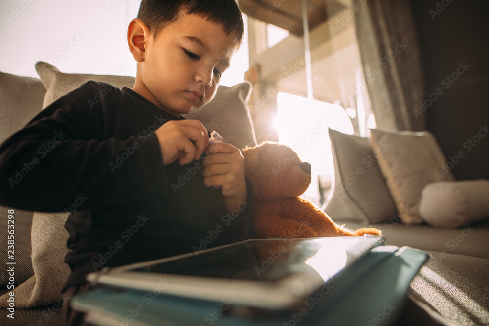 Innocent kid at home with digital tablet