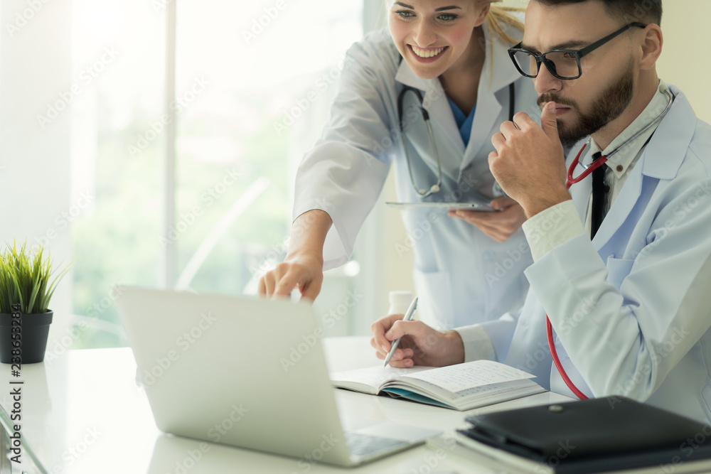 Two doctors analysing and consulting over medical record in modern hospital. Caucasian doctors talki