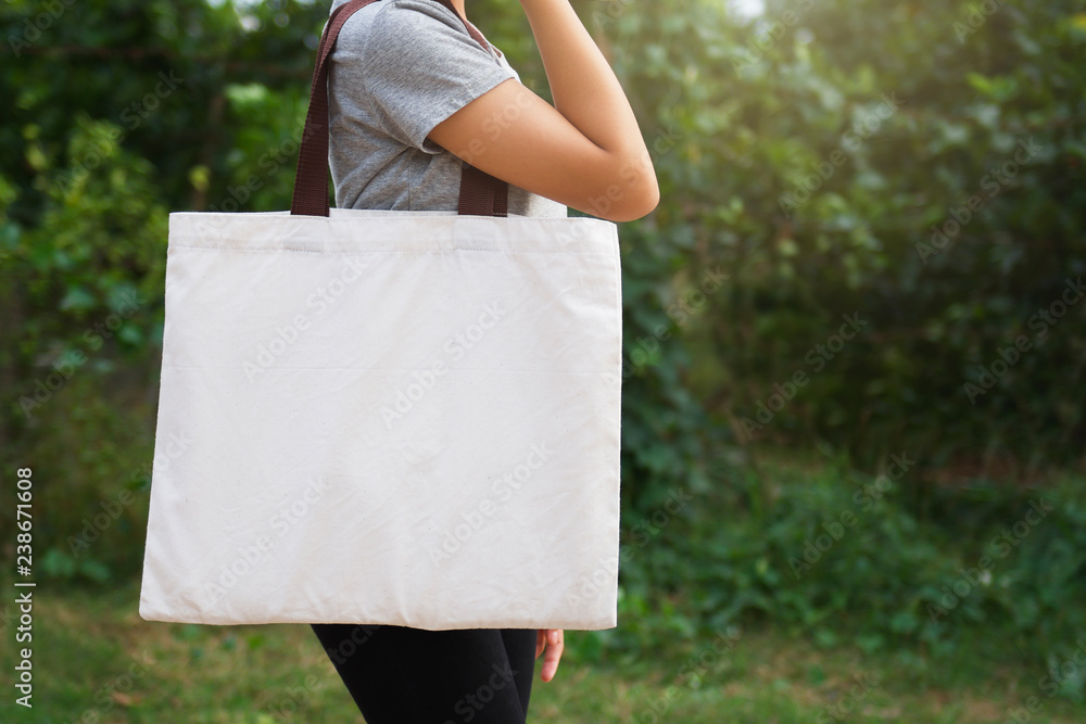 woman hand holding cotton bag on green background. eco concept