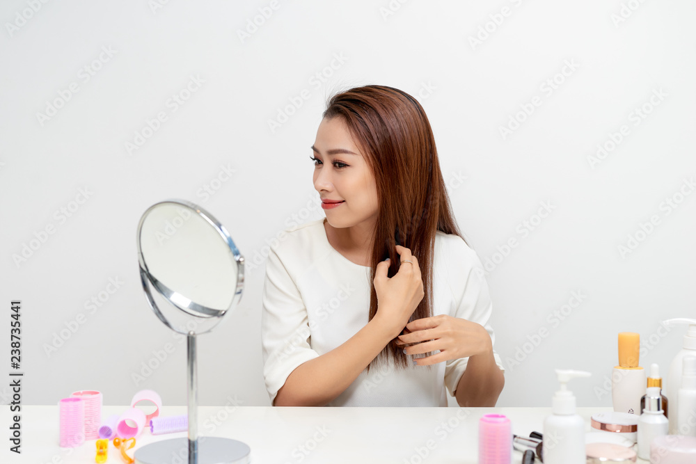 Portrait of brunette woman looking at her face in mirror