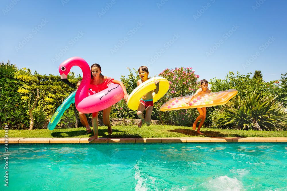 Friends with swim tools running to swimming pool