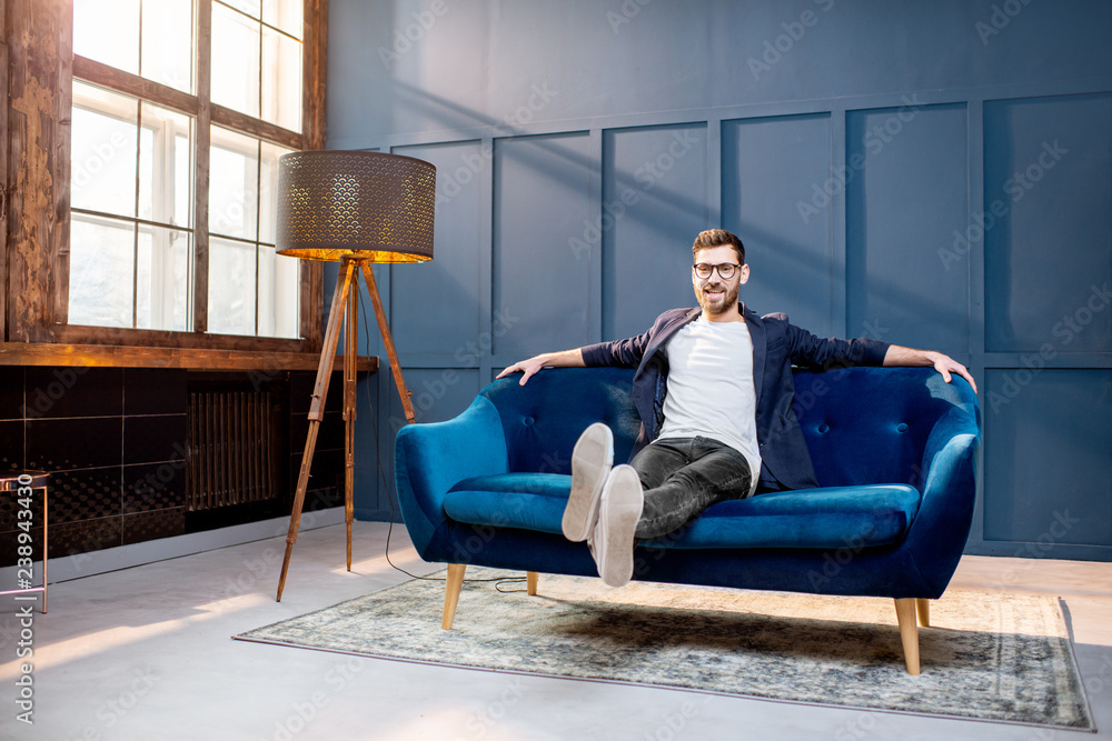 Portrait of relaxed businessman dressed casualy sitting on the couch at the luxury office with blue 