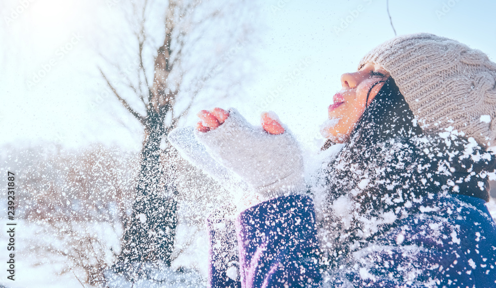 冬季女孩肖像。美丽快乐的模特女孩吹雪，在冬季公园玩得很开心。美丽的哟