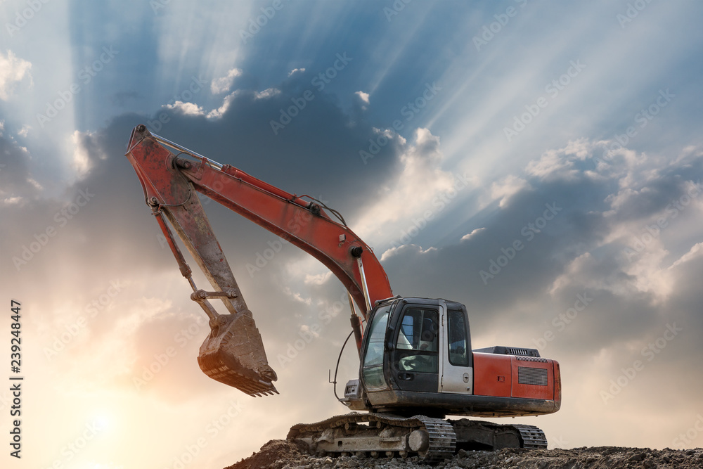 Excavator in construction site on sunset sky background