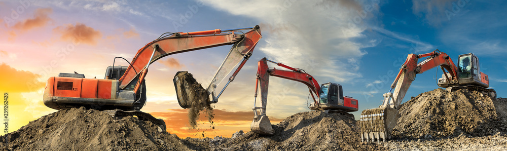 Three excavators work on construction site at sunset,panoramic view