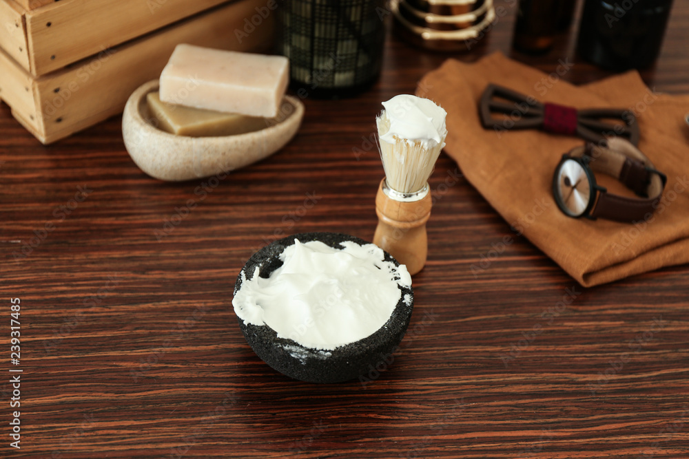 Shaving brush and bowl with foam on wooden table