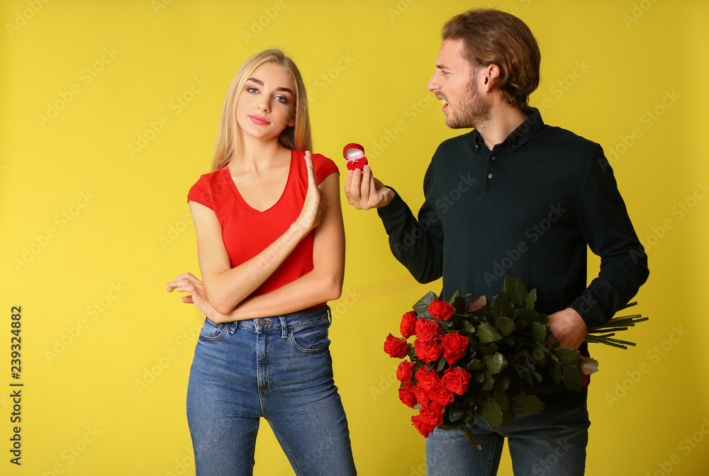 Young woman rejecting marriage proposal on color background