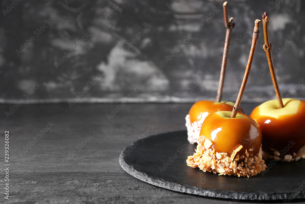 Delicious caramel apples with tree branches on slate plate