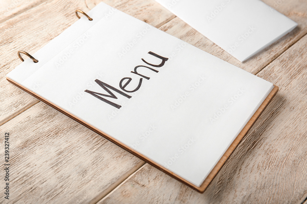 Notebook with menu on wooden table