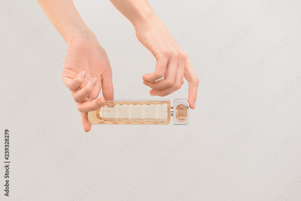 Woman holding bottle of perfume on color background