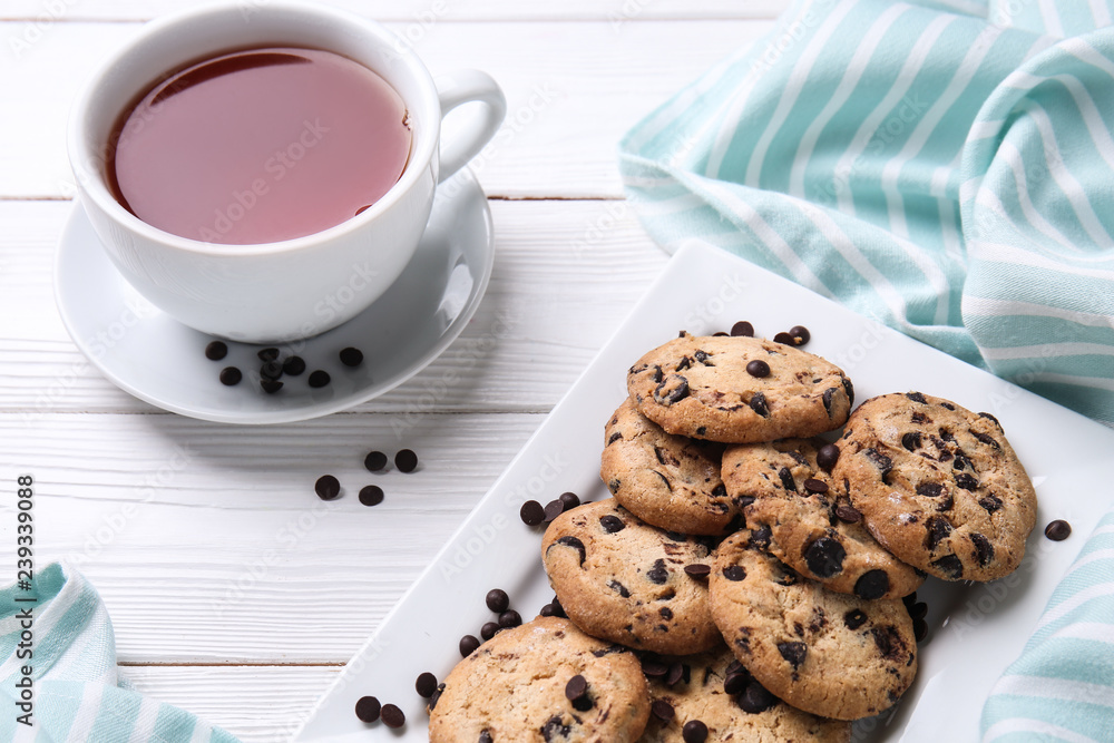 白色木桌上的美味饼干、巧克力片和一杯茶