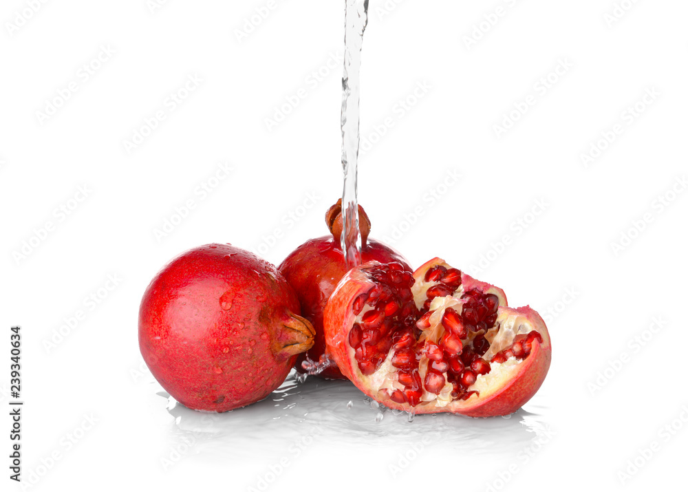 Fresh pomegranates with splashing water on light background