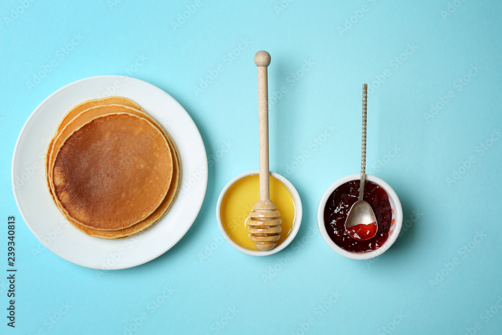 Plate with hot tasty pancakes, honey and jam on color background