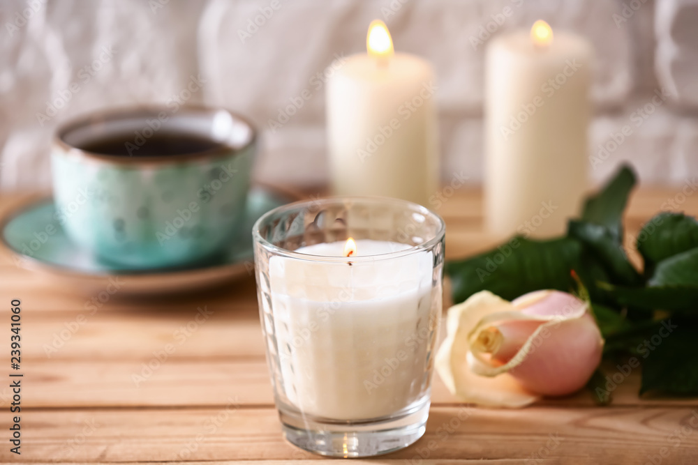 Burning candle and rose flower on wooden table