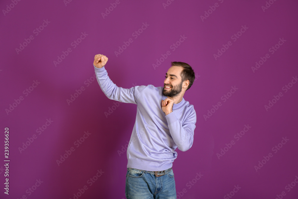 Handsome young man dancing on color background