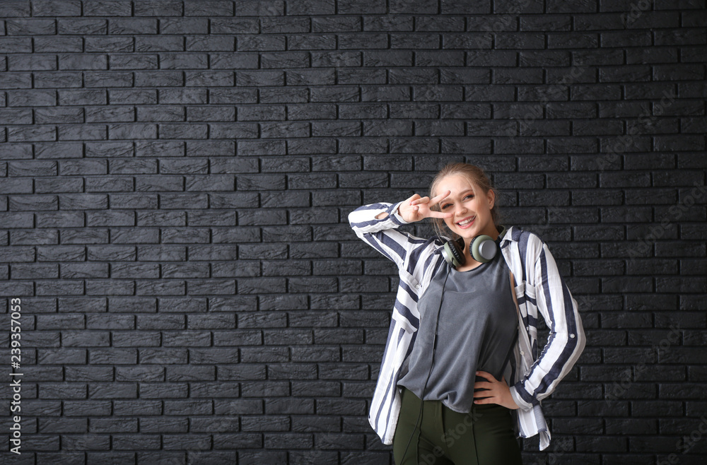 Beautiful young woman dancing against dark brick wall