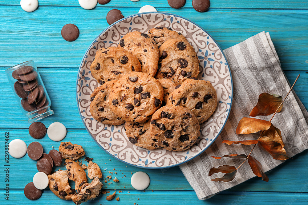 Plate with tasty chocolate chip cookies on color wooden table