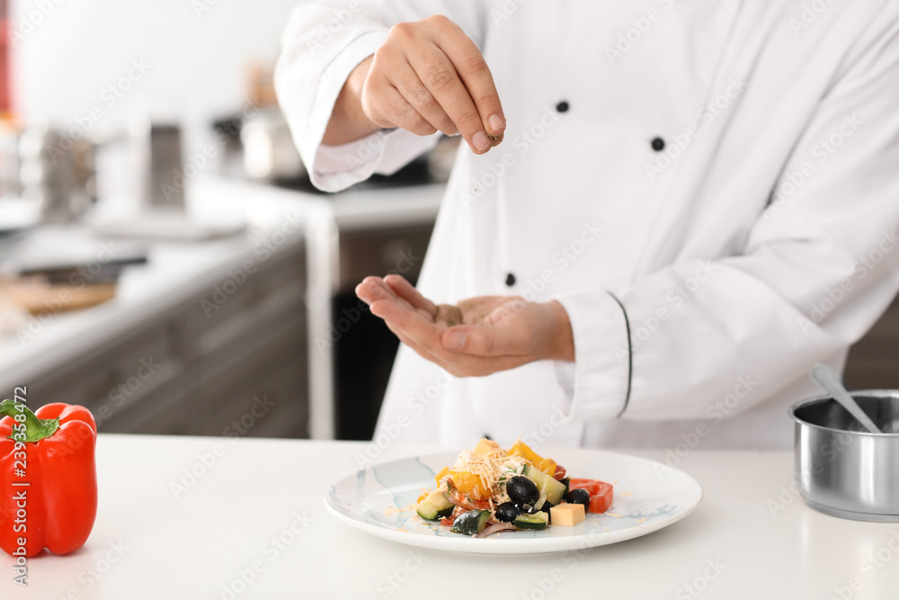 男厨师在厨房为美味沙拉添加香料，特写