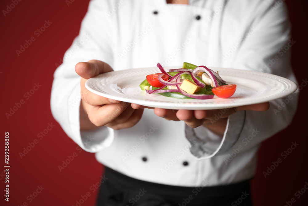 Male chef with tasty salad on color background, closeup