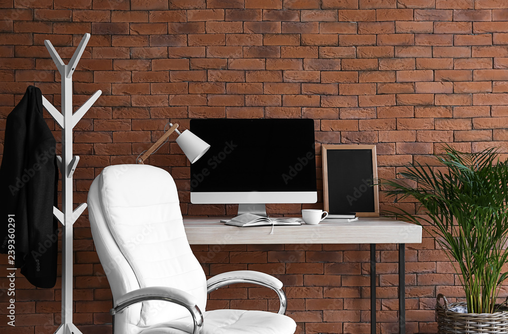 Stylish workplace with modern computer near brick wall