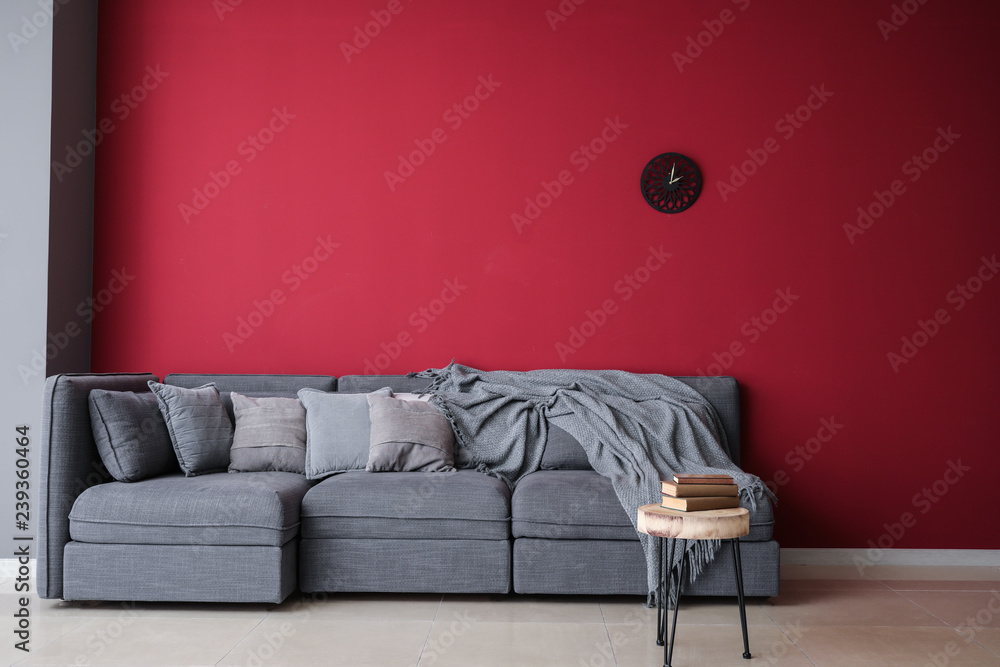 Stylish interior of room with comfortable big sofa near color wall