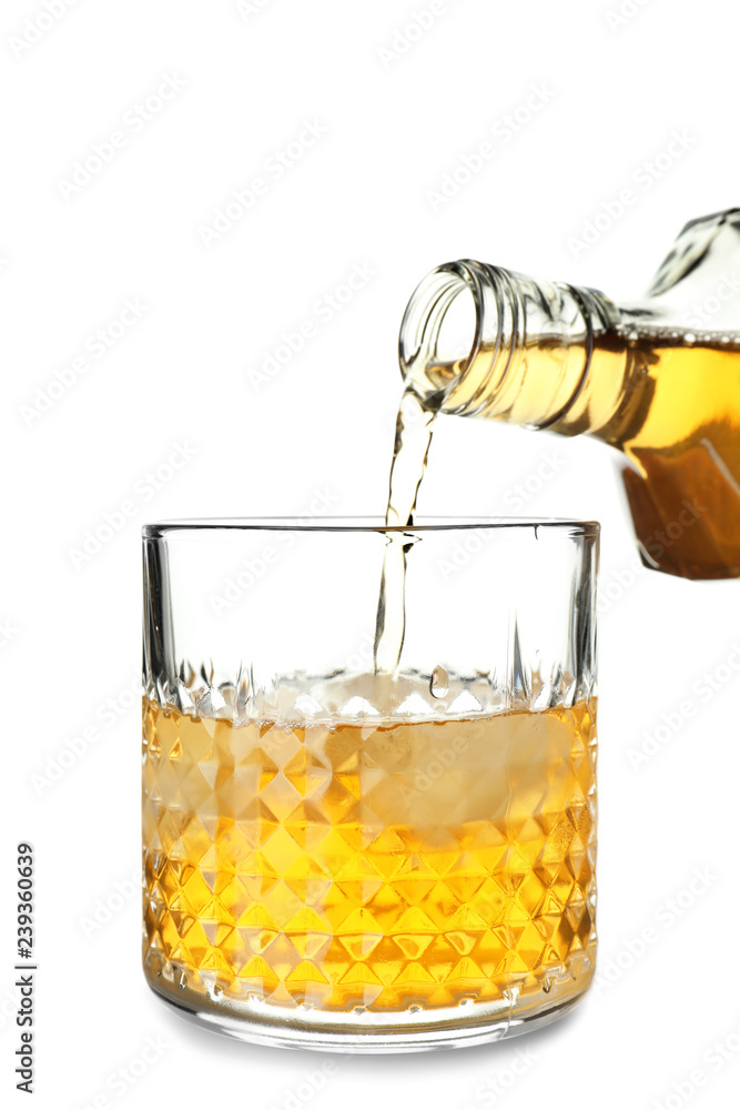 Pouring of cold whiskey from bottle into glass on white background