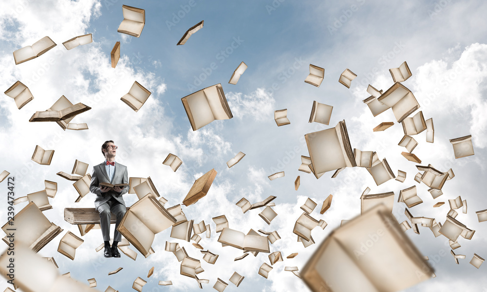 Young businessman or student studying the science and books fly around