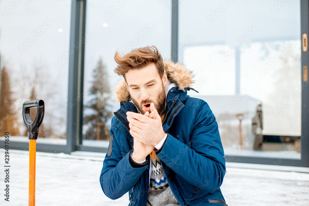 一个穿着冬装的英俊男子坐在现代房子的露台上的肖像