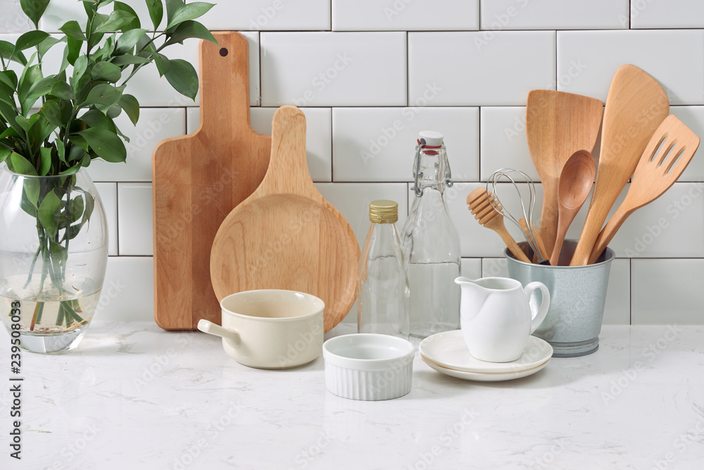 Simple rustic kitchenware against white wooden wall: rough ceramic pot with wooden cooking utensil s