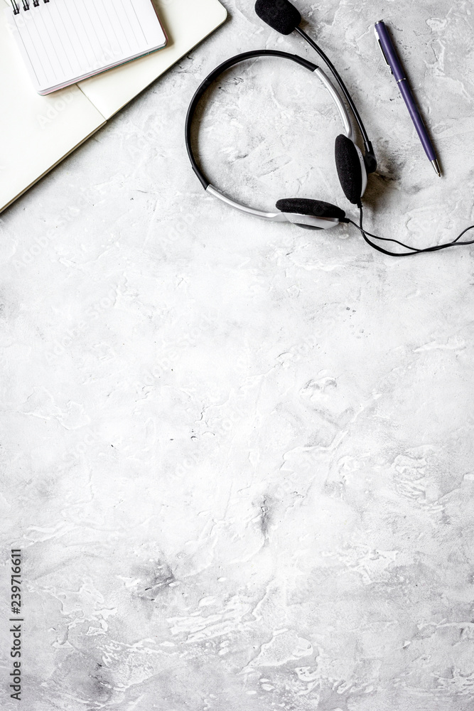 Office desk with headset and keyboard stone background top view 