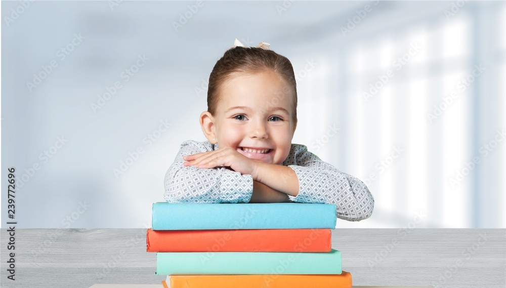 Little cute girl with books near green blackboard