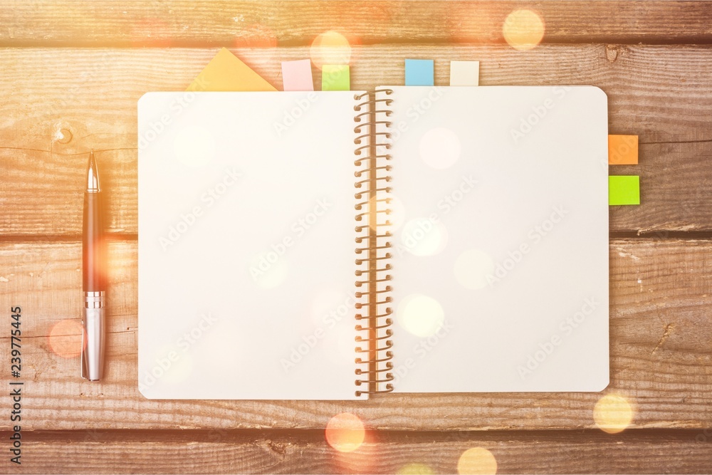 Blank notebook and pen on wooden background