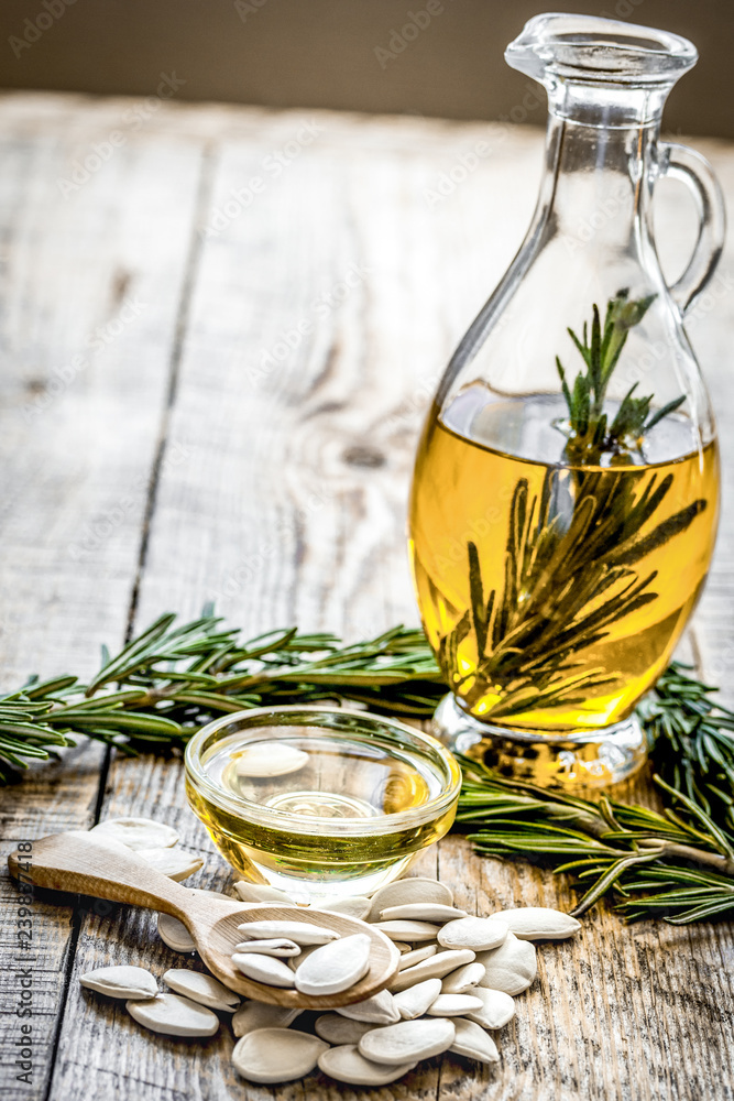 Bottle with pumpkin seeds oil and herbs on wooden background